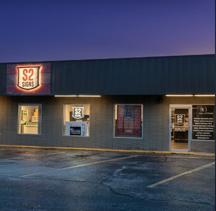 The S2 Sign Solutions storefront on Fort Campbell Boulevard, signage illuminated at dusk